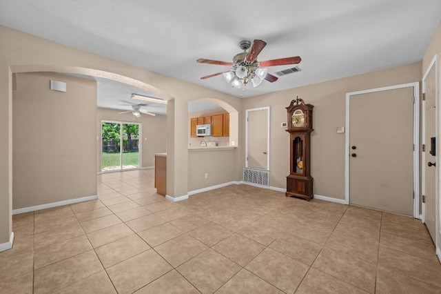 141 Britni Loop, Kyle, TX 78640 - empty room with a ceiling fan, arched walkways, light tile patterned floors, and baseboards
