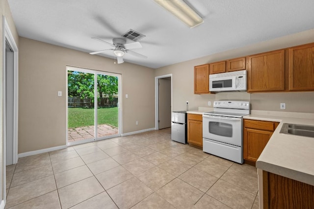kitchen featuring white appliances, a ceiling fan, light countertops, light tile patterned floors, and brown cabinetry