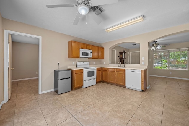 141 Britni Loop, Kyle, TX 78640 - kitchen with white appliances, a ceiling fan, a sink, light countertops, and arched walkways