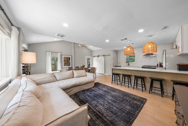 1302 Astor Pl, Austin, TX 78721 - living area with a barn door, light wood-style floors, healthy amount of natural light, recessed lighting, and vaulted ceiling
