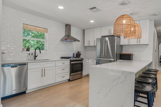1302 Astor Pl, Austin, TX 78721 - kitchen with appliances with stainless steel finishes, wall chimney exhaust hood, a sink, a peninsula, and decorative backsplash