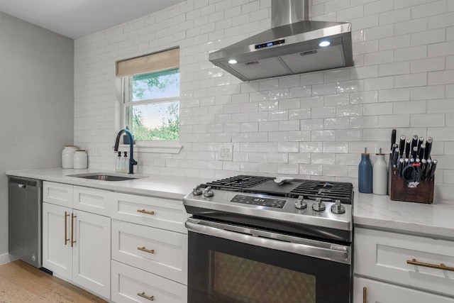 1302 Astor Pl, Austin, TX 78721 - kitchen featuring appliances with stainless steel finishes, wall chimney exhaust hood, a sink, decorative backsplash, and light stone counters