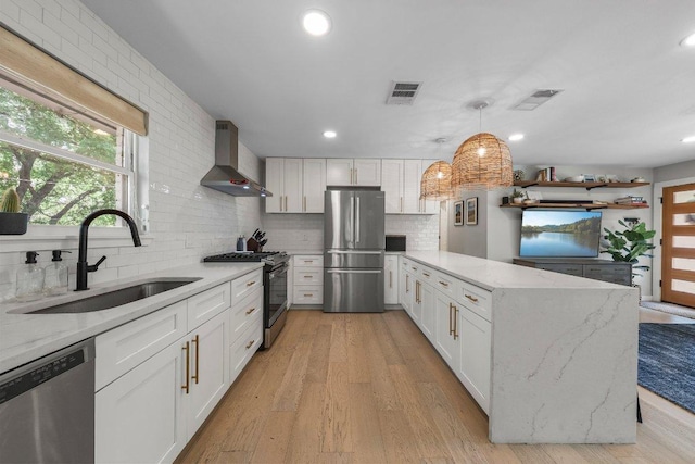 1302 Astor Pl, Austin, TX 78721 - kitchen with appliances with stainless steel finishes, wall chimney exhaust hood, a sink, a peninsula, and backsplash