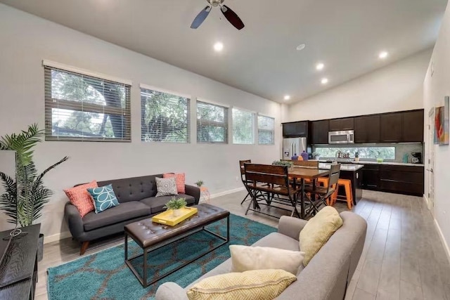 living area with a ceiling fan, recessed lighting, baseboards, lofted ceiling, and light wood-style floors
