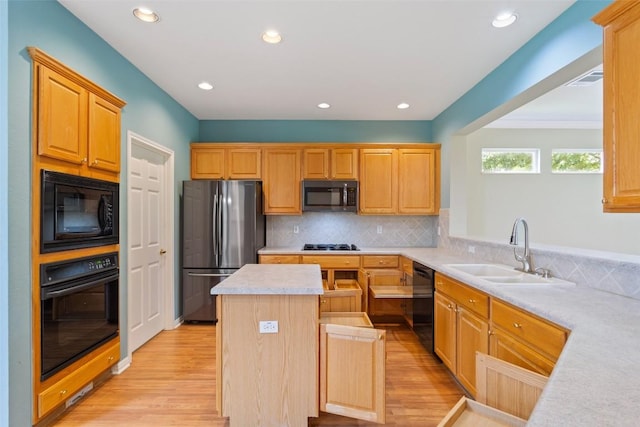 138 Dewberry Dr, Georgetown, TX 78633 - kitchen with black appliances, a sink, light wood-style floors, a kitchen island, and light countertops