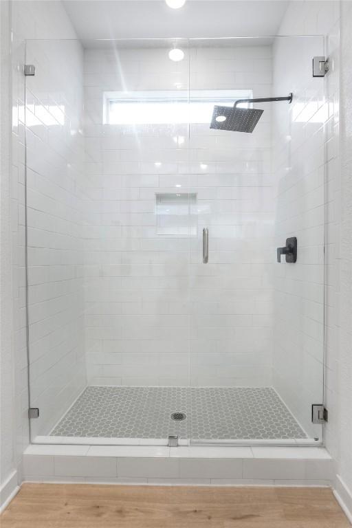 full bath featuring wood finished floors and a shower stall