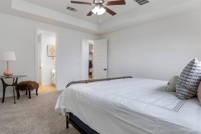 bedroom featuring a raised ceiling, carpet, baseboards, a ceiling fan, and ensuite bath