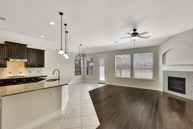 441 Cascada Ln, Round Rock, TX 78681 - kitchen featuring open floor plan, under cabinet range hood, a sink, stainless steel gas cooktop, and light stone countertops