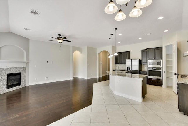 kitchen featuring appliances with stainless steel finishes, open floor plan, arched walkways, ceiling fan, and recessed lighting