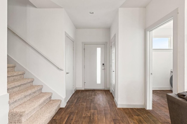 entryway featuring dark wood-type flooring, washer / dryer, baseboards, and stairs