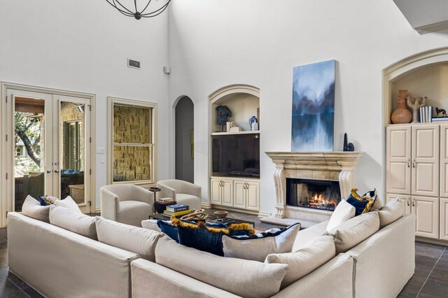 5902 Saratoga Cv, Austin, TX 78746 - living area featuring french doors, a towering ceiling, a fireplace, built in shelves, and arched walkways