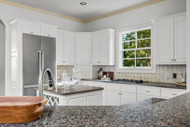 5902 Saratoga Cv, Austin, TX 78746 - kitchen with high quality fridge, dark stone counters, white cabinetry, and ornamental molding