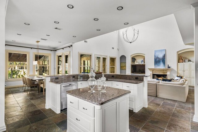 5902 Saratoga Cv, Austin, TX 78746 - kitchen with stainless steel dishwasher, a center island, stone tile floors, a lit fireplace, and recessed lighting