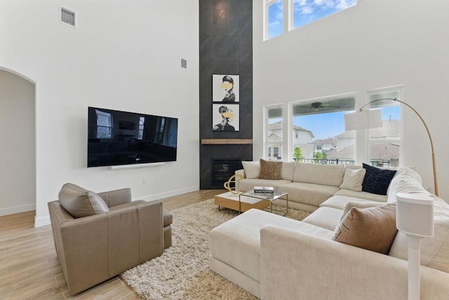 living area featuring a high ceiling, baseboards, arched walkways, and light wood-style floors