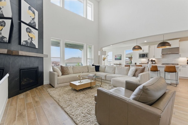 604 Buena Onda Way, Lakeway, TX 78738 - living area with light wood-style flooring, a towering ceiling, and a tile fireplace