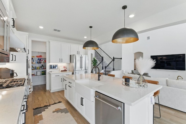 604 Buena Onda Way, Lakeway, TX 78738 - kitchen with appliances with stainless steel finishes, open floor plan, arched walkways, light wood-type flooring, and recessed lighting