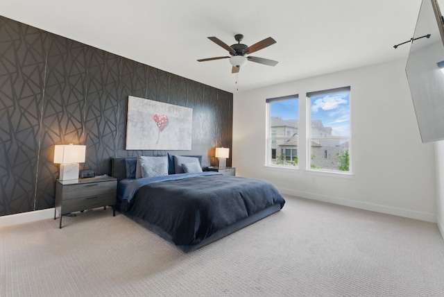carpeted bedroom with baseboards, an accent wall, and ceiling fan