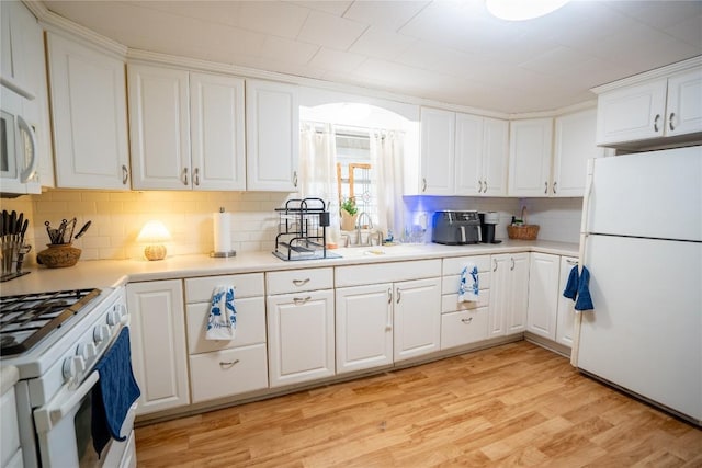 1705 Old Thorndale Rd, Taylor, TX 76574 - kitchen featuring white appliances, backsplash, white cabinetry, a sink, and light wood-type flooring