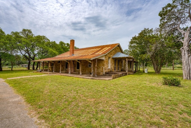 624 N US Highway 281, Johnson City, TX 78636 - view of front of home with a chimney, stone siding, metal roof, a front lawn, and a porch