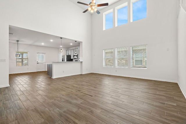 1100 Whipple Tree Trl, Georgetown, TX 78626 - unfurnished living room featuring plenty of natural light, a ceiling fan, dark wood finished floors, a high ceiling, and baseboards