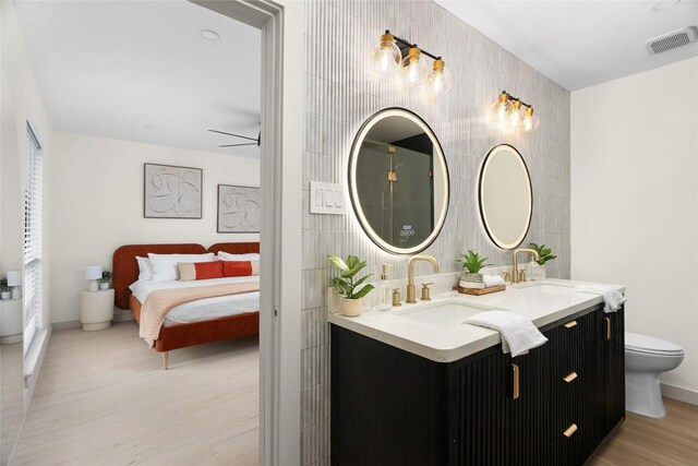 2209 Forest Bend Dr, Austin, TX 78704 - full bathroom featuring double vanity, wood finished floors, ensuite bathroom, an accent wall, and tile walls