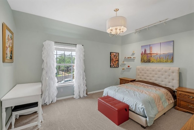 carpeted bedroom with a chandelier, track lighting, and baseboards