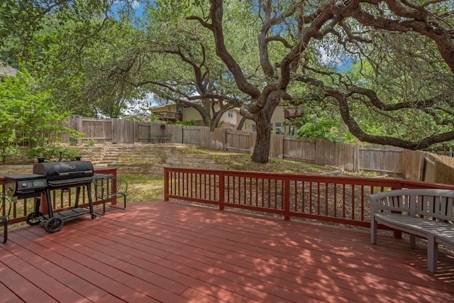 wooden deck with a fenced backyard and a grill