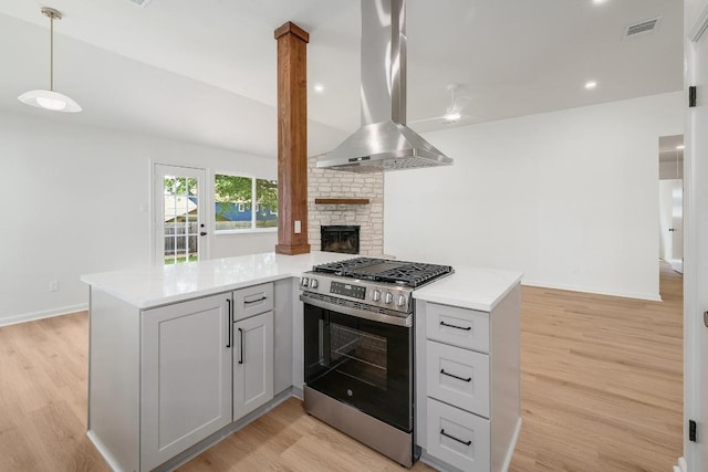 2602 Water Well Ln, Austin, TX 78728 - kitchen with stainless steel range with gas stovetop, island exhaust hood, a peninsula, and light wood finished floors
