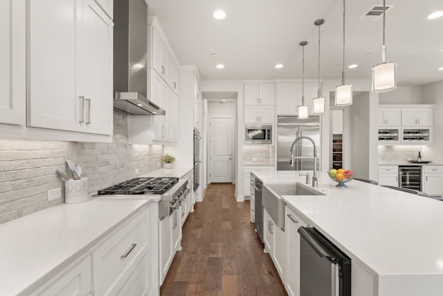 kitchen featuring a sink, built in appliances, wall chimney range hood, a large island, and light countertops
