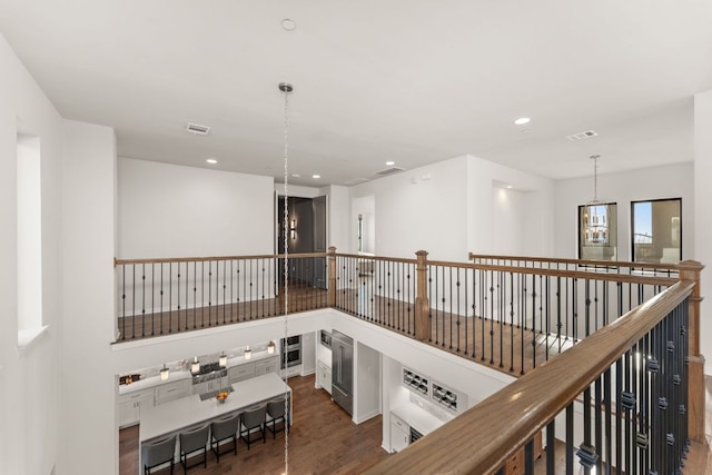 hallway featuring wood finished floors, recessed lighting, an upstairs landing, and a chandelier