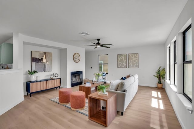 8921 Norwich Castle, Austin, TX 78747 - living room with a glass covered fireplace, light wood-style floors, ceiling fan, and baseboards