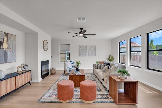 8921 Norwich Castle, Austin, TX 78747 - living area featuring a glass covered fireplace, light wood-style floors, baseboards, and ceiling fan