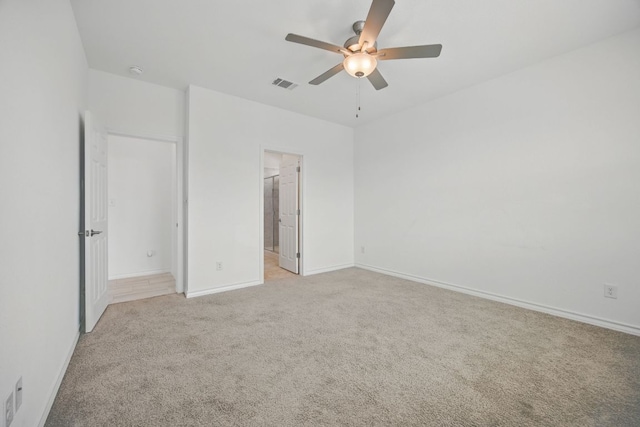 unfurnished bedroom featuring light carpet, baseboards, a ceiling fan, and ensuite bathroom