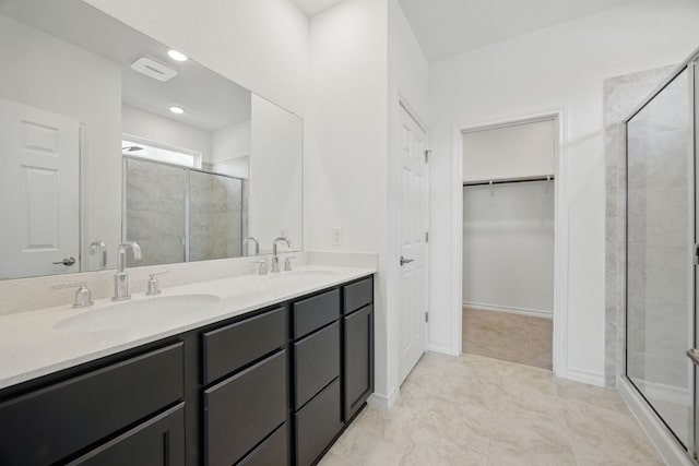 full bath featuring a shower stall, a walk in closet, and double vanity