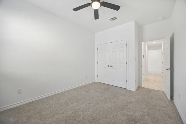 unfurnished bedroom with carpet floors, a closet, baseboards, and a ceiling fan
