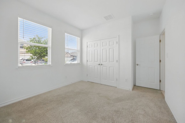 unfurnished bedroom with light colored carpet, a closet, and baseboards