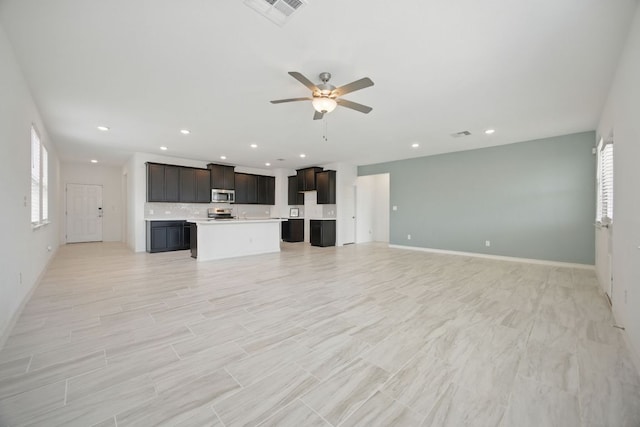 unfurnished living room featuring plenty of natural light, ceiling fan, recessed lighting, and baseboards