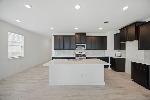209 Thurman Holt Rd, Hutto, TX 78634 - kitchen with stainless steel appliances, a sink, a center island with sink, decorative backsplash, and recessed lighting
