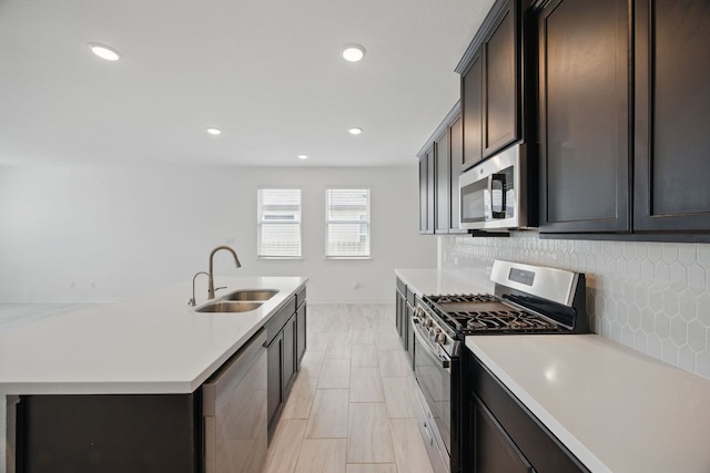 kitchen with appliances with stainless steel finishes, a sink, light countertops, tasteful backsplash, and dark brown cabinets