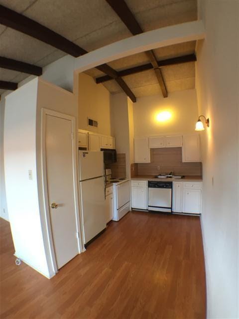 2404 Longview St Unit 205, Austin, TX 78705 - kitchen featuring white appliances, beam ceiling, white cabinets, high vaulted ceiling, and wood finished floors
