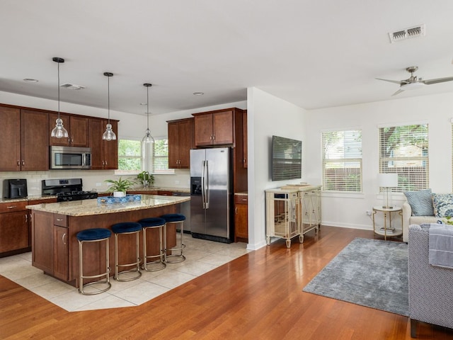 1200 Marcy St, Austin, TX 78704 - kitchen with stainless steel appliances, a kitchen island, decorative backsplash, light wood-style floors, and recessed lighting