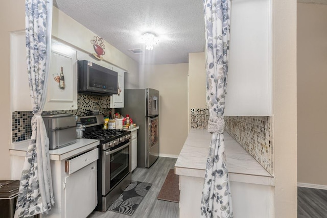 9801 Oriole Dr, Austin, TX 78753 - kitchen featuring stainless steel appliances, light wood finished floors, a textured ceiling, decorative backsplash, and light countertops