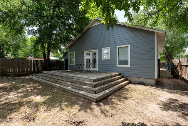 rear view of house with french doors, a wooden deck, and a fenced backyard