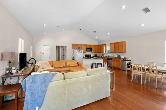 living area with wood finished floors, recessed lighting, and high vaulted ceiling