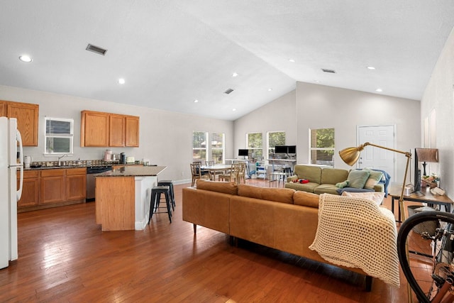 living area featuring wood finished floors, high vaulted ceiling, and recessed lighting