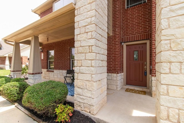 entrance to property with brick siding, covered porch, and stone siding