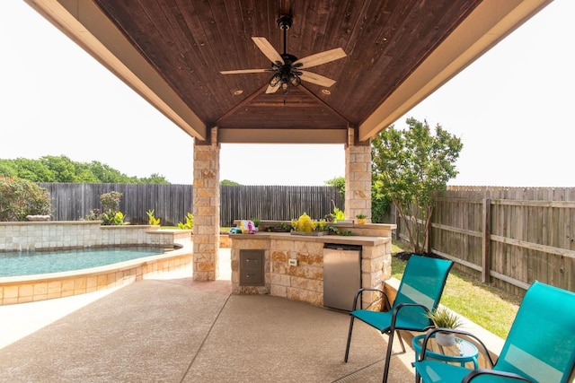 view of patio / terrace featuring a fenced backyard, ceiling fan, and exterior kitchen