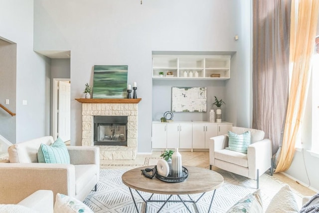 living room featuring light tile patterned flooring, a stone fireplace, and baseboards