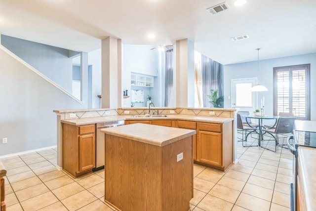 kitchen with a center island, stainless steel appliances, light countertops, light tile patterned flooring, and a sink