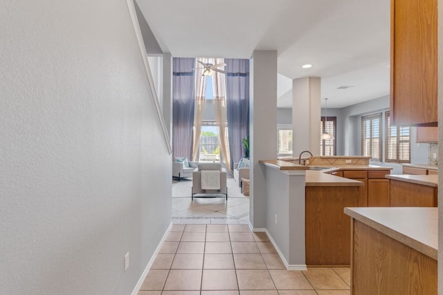 kitchen with light countertops, a sink, light tile patterned floors, and baseboards